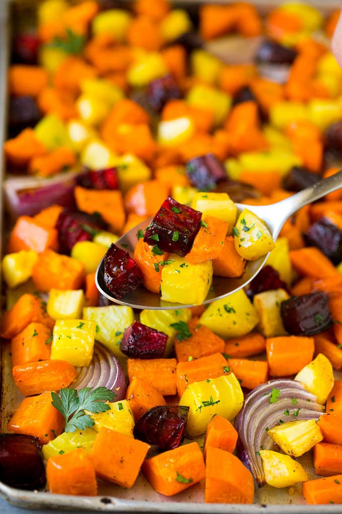 Roasted Root Vegetables Recipe | Roasted Sweet Potatoes | Roasted Beets | Roasted Carrots #carrots #beets #vegetables #sweetpotatoes #fall #parsnips #sidedish #sraye #cleaneating #healthy A spoon serving up a portion of roasted vegetables.