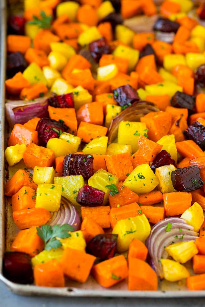 Roasted Root Vegetables Recipe | Roasted Sweet Potatoes | Roasted Beets | Roasted Carrots #carrots #beets #vegetables #sweetpotatoes #fall #parsnips #sidedish #sraye #cleaneating #healthy Roasted root vegetables on a sheet pan, topped with chopped parsley.