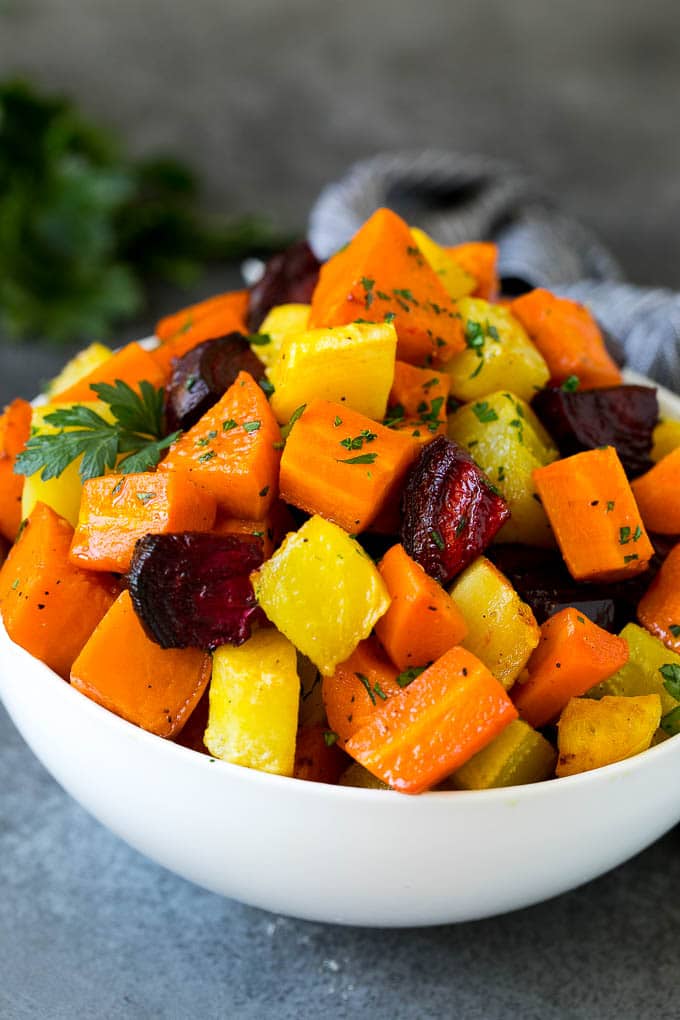 Roasted Root Vegetables Recipe | Roasted Sweet Potatoes | Roasted Beets | Roasted Carrots #carrots #beets #vegetables #sweetpotatoes #fall #parsnips #sidedish #sraye #cleaneating #healthy A bowl of diced roasted root vegetables topped with parsley.