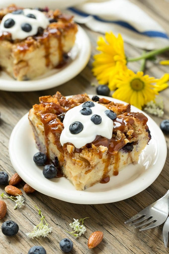 Blueberry Bread Pudding Recipe | Blueberry Bread Pudding | Easy Bread Pudding #blueberry #breadpudding #dessert #sraye Slices of bread pudding on plates, topped with caramel and fresh berries.
