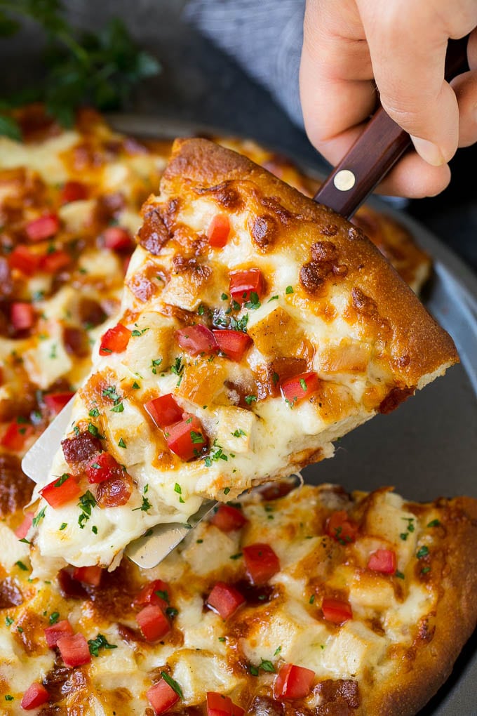 Chicken Alfredo Pizza Recipe #pizza #chicken #bacon #dinner #sraye A hand holding a spatula with a piece of chicken Alfredo pizza on it.