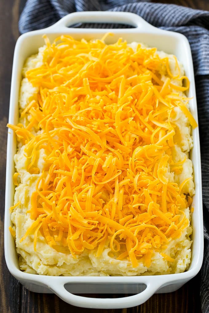 Loaded Mashed Potato Casserole Recipe | Loaded Potatoes | Bacon Mashed Potatoes | Thanksgiving Mashed Potatoes #potatoes #bacon #cheese #casserole #Thanksgiving #dinner #sraye Mashed potatoes in a casserole dish, topped with shredded cheese.