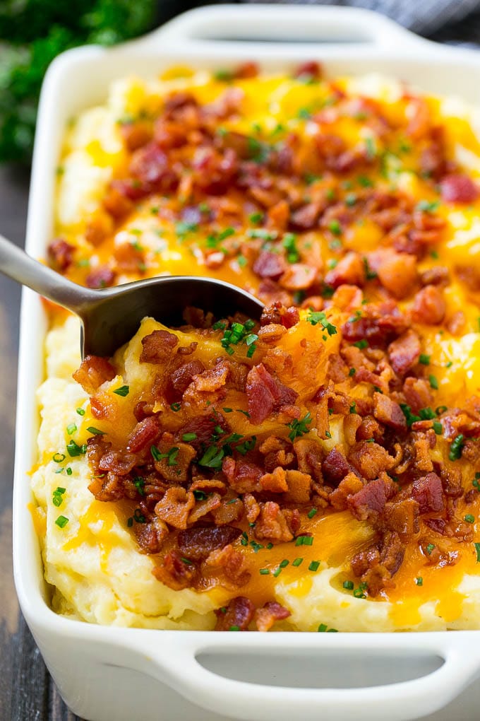 Loaded Mashed Potato Casserole Recipe | Loaded Potatoes | Bacon Mashed Potatoes | Thanksgiving Mashed Potatoes #potatoes #bacon #cheese #casserole #Thanksgiving #dinner #sraye A dish of loaded mashed potato casserole with a serving spoon in it.