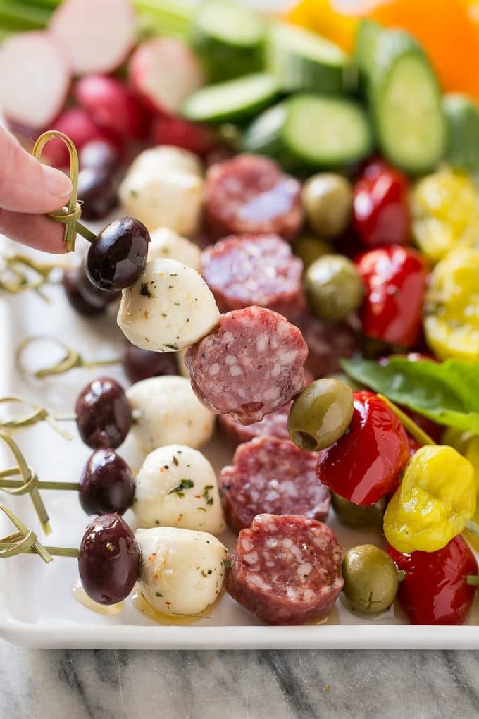 Antipasto Skewers Recipe | Easy Antipasto | Best Antipasto #antipasto #skewers #appetizer #sraye A hand holding up a skewer of salami, cheese and olives.