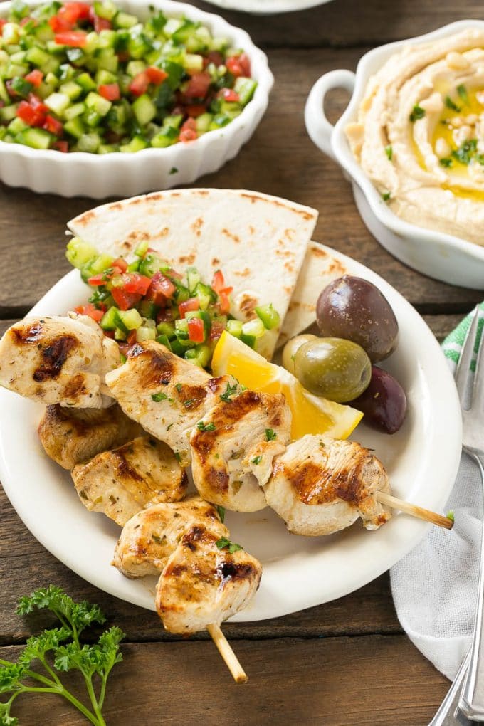 Greek Chicken Souvlaki Recipe | Easy Greek Chicken | Chicken Souvlaki | Greek Chicken Skewers | Easy Greek Chicken Skewers #chicken #kabobs #glutenfree #keto #lowcarb #grilling #sraye A plate of skewers with olives and pita bread.