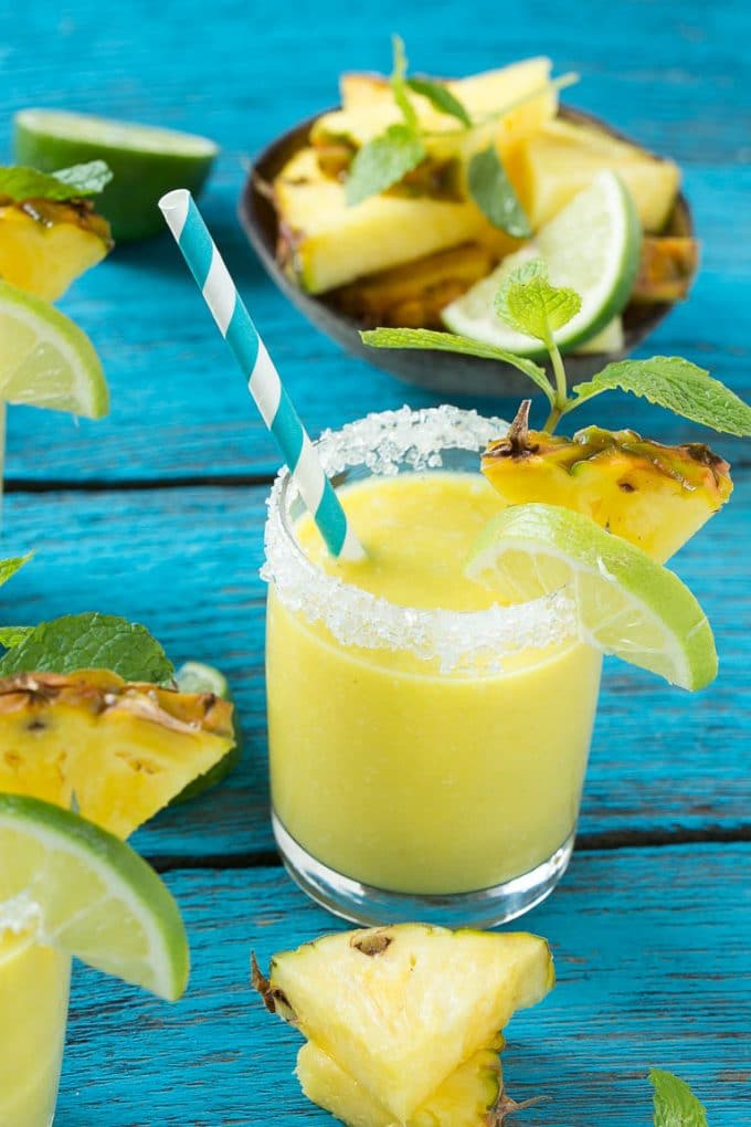 Pineapple Coconut Smoothie Recipe |Tropical Smoothie | Pineapple Smoothie #smoothie #pineapple #coconut #healthy #cleaneating #sraye A tropical smoothie with a paper straw in it.