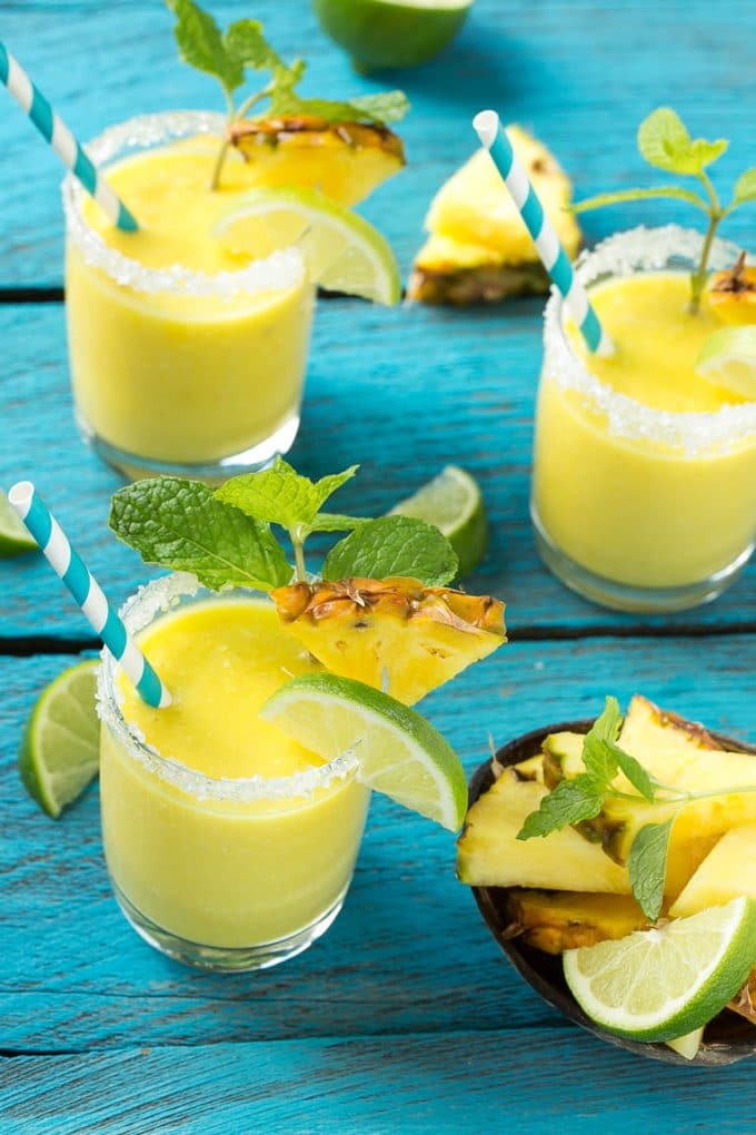 Pineapple Coconut Smoothie Recipe |Tropical Smoothie | Pineapple Smoothie #smoothie #pineapple #coconut #healthy #cleaneating #sraye Pineapple coconut smoothies in glasses with sugared rims.