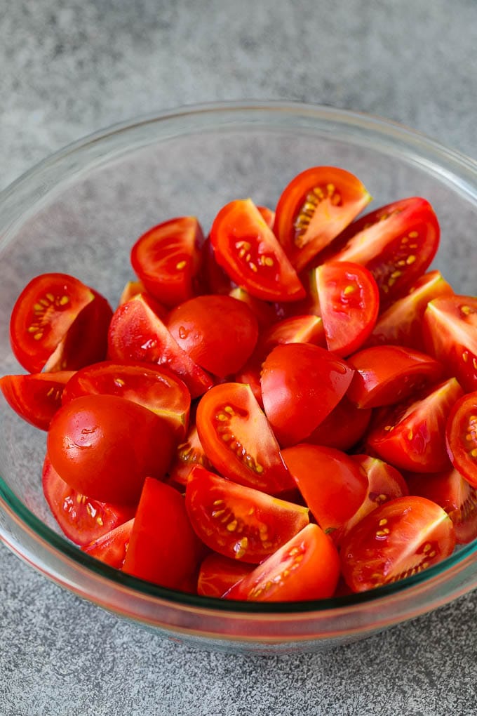 Caprese Salad Recipe | Tomato Salad #salad #tomato #mozzarella #cheese #basil #caprese #summer #sraye Quartered tomatoes in a bowl.