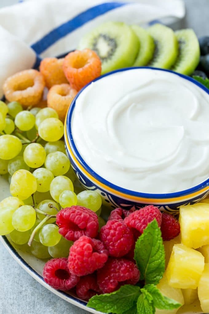 Cream Cheese Fruit Dip | Fruit Recipe | Fruit Dip #fruit #dip #creamcheese #snack #dessert #sraye A bowl of cream cheese fruit dip surrounded by grapes, raspberries and kiwis.