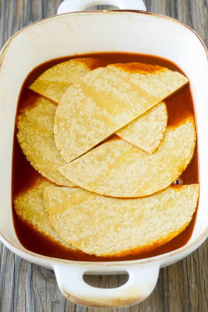 Chicken Enchilada Casserole Recipe | Chicken Enchiladas | Easy Casserole Recipe | Enchilada Casserole #chicken #casserole #enchiladas #cheese #beans #dinner #sraye Corn tortillas and enchilada sauce in a casserole dish.