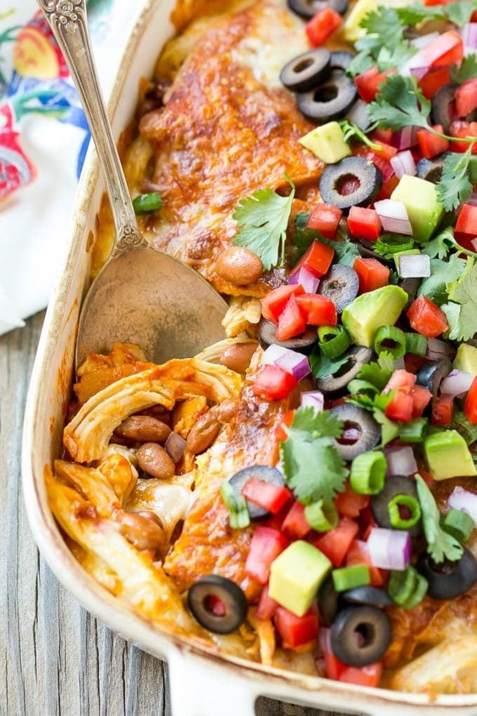 Chicken Enchilada Casserole Recipe | Chicken Enchiladas | Easy Casserole Recipe | Enchilada Casserole #chicken #casserole #enchiladas #cheese #beans #dinner #sraye A chicken enchilada casserole with a serving spoon in it.