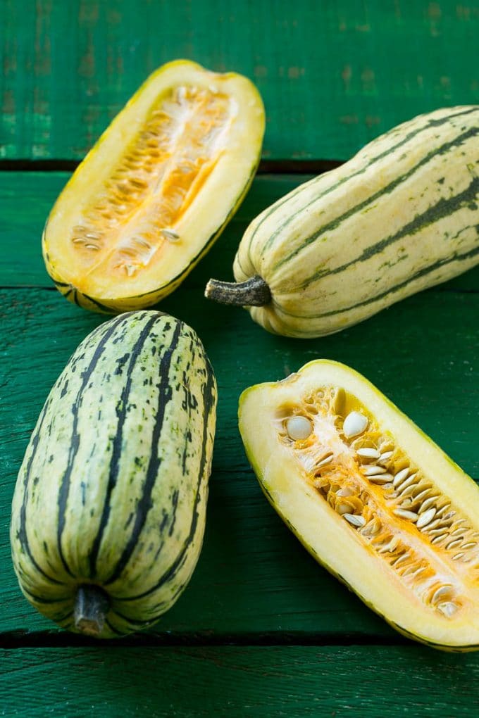 Brown Sugar Delicata Squash Recipe | Roasted Squash | Delicata Squash | Winter Squash Recipe #squash #wintersquash #brownsugar #sidedish #delicatasquash #dinner #sraye Raw delicata squash on a green board.