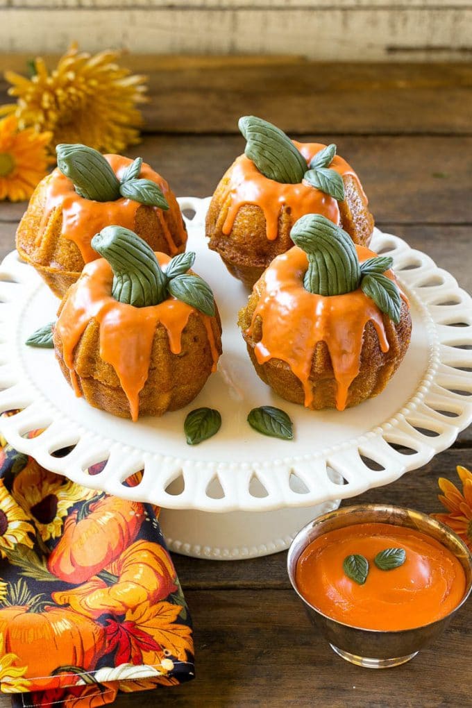 Pumpkin Spice Cake Recipe | Pumpkin Cake | Easy Pumpkin Cake | Thanksgiving Dessert #thanksgiving #pumpkin #cake #pumpkincake #spicecake #dessert #sraye #holiday Pumpkin spice cake topped with orange glaze and fondant decorations on a serving platter.