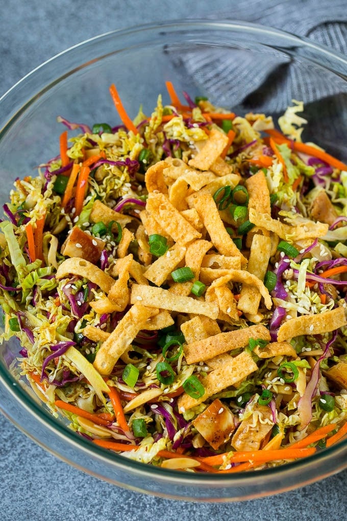 Chinese Chicken Salad Recipe | Asian Chicken Salad #salad #chicken #chickensalad #cabbage #lunch #dinner #sraye A bowl of Chinese chicken salad topped with wontons and sesame seeds.
