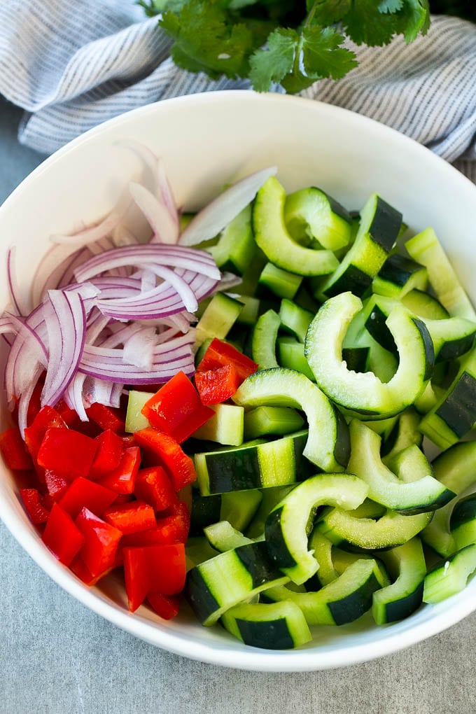 Asian Cucumber Salad Recipe | Sesame Cucumber Salad | Cucumber Salad | Healthy Salad | Healthy Cucumber Recipe #cucumber #cucumbersalad #salad #sidedish #sraye Sliced cucumbers, red peppers and red onion in a serving bowl.