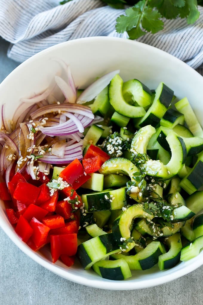 Asian Cucumber Salad Recipe | Sesame Cucumber Salad | Cucumber Salad | Healthy Salad | Healthy Cucumber Recipe #cucumber #cucumbersalad #salad #sidedish #sraye Sliced cucumbers, red peppers and onions with dressing.