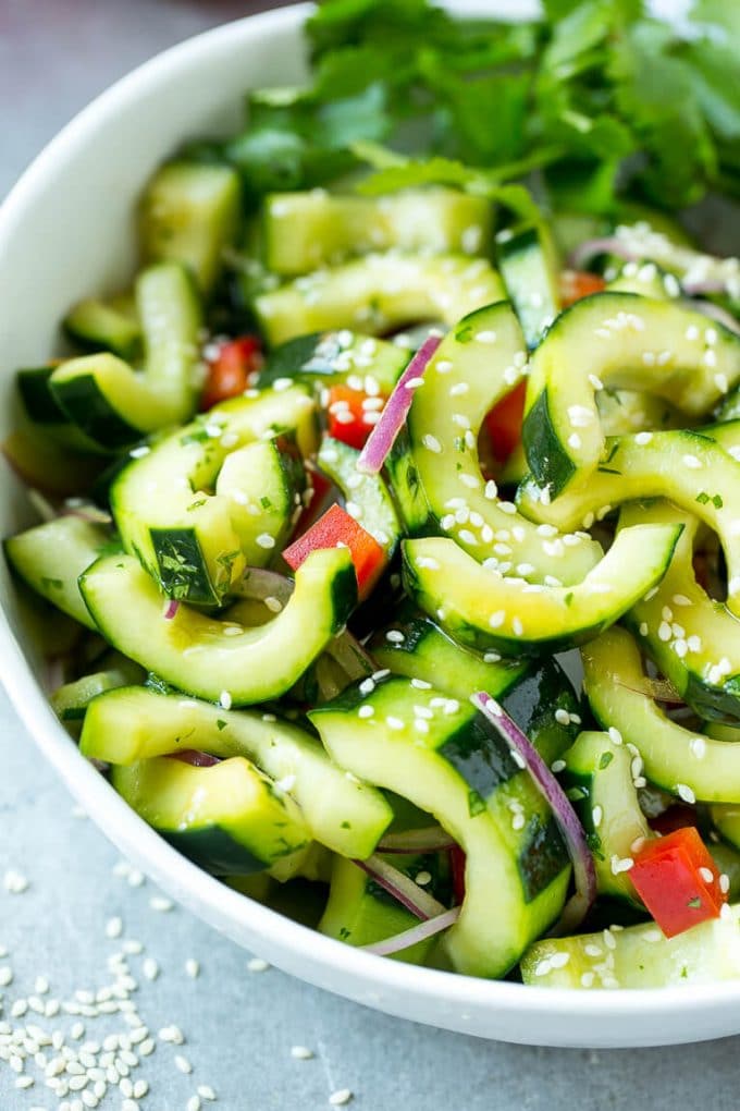 Asian Cucumber Salad Recipe | Sesame Cucumber Salad | Cucumber Salad | Healthy Salad | Healthy Cucumber Recipe #cucumber #cucumbersalad #salad #sidedish #sraye A bowl of Asian cucumber salad with dressing and sesame seeds on top.