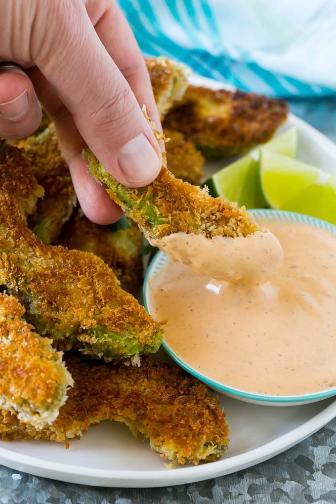 Avocado Fries Recipe | Fried Avocado | Avocado Fritters #avocado #appetizer #snack #sraye A hand dipping an avocado fry into sauce.