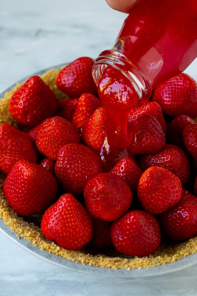 No Bake Strawberry Pie Recipe | Fresh Strawberry Pie | Strawberry Pie Recipe | No Bake Pie Recipe #strawberry #strawberrypie #nobake #nobakepie #dessert #sraye Glaze being poured over a strawberry pie.