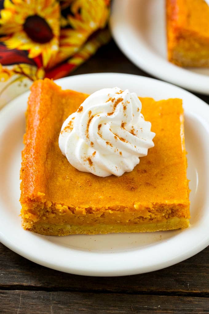 Pumpkin Gooey Butter Cake Recipe | Pumpkin Cake Recipe | Gooey Butter Cake | Pumpkin Dessert | Thanksgiving Dessert #pumpkin #cake #pumpkincake #gooeybuttercake #dessert #sraye A slice of pumpkin gooey butter cake topped with whipped cream.