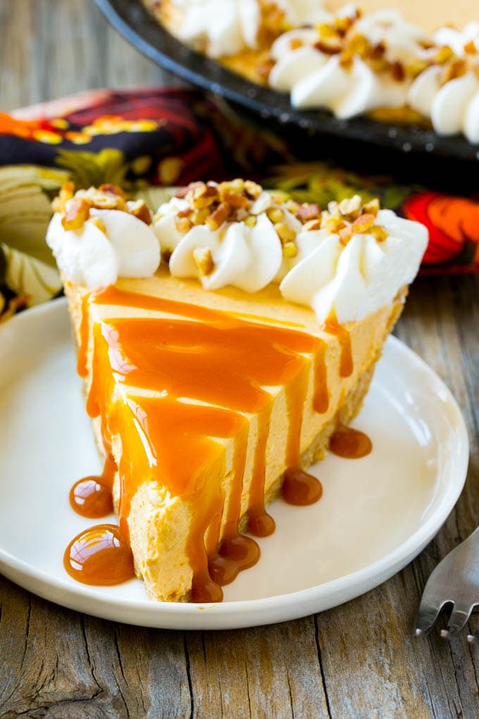 No Bake Pumpkin Cheesecake Recipe | Pumpkin Cheesecake | No Bake Cheesecake | Thanksgiving Dessert | Pumpkin Dessert #nobake #cheesecake #pumpkin #pumpkinpie #pumpkincheesecake #nobakecheesecake #dessert #sraye A slice of cheesecake topped with a caramel drizzle.