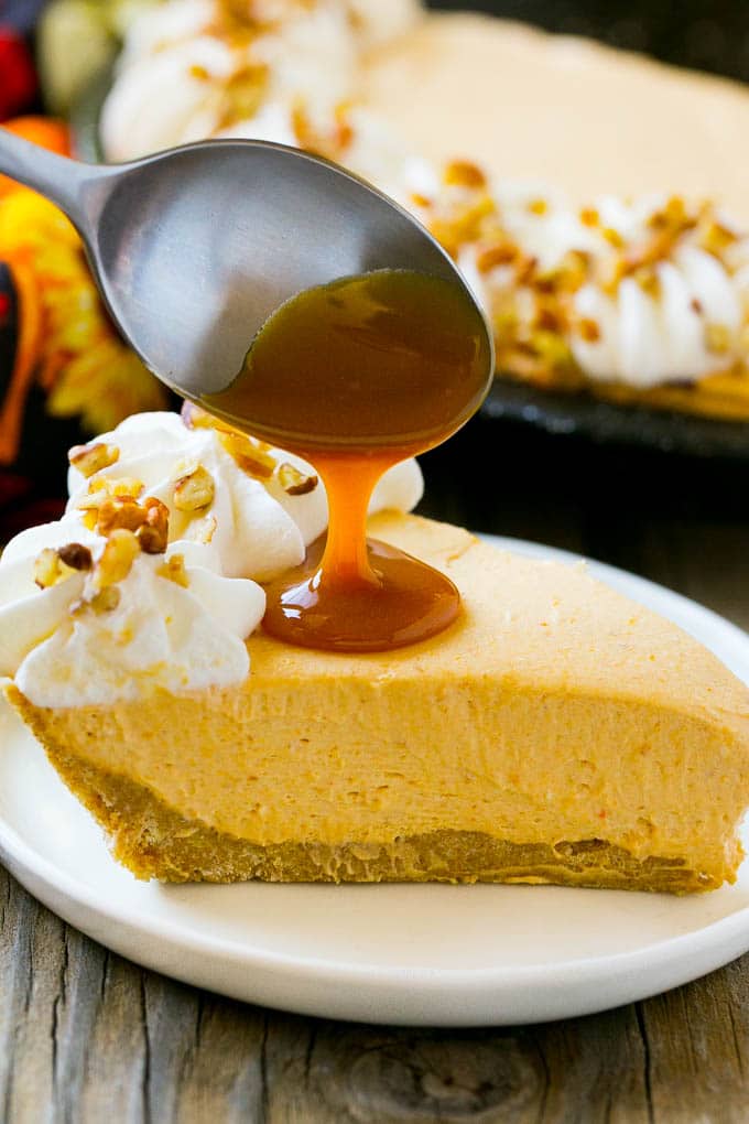 No Bake Pumpkin Cheesecake Recipe | Pumpkin Cheesecake | No Bake Cheesecake | Thanksgiving Dessert | Pumpkin Dessert #nobake #cheesecake #pumpkin #pumpkinpie #pumpkincheesecake #nobakecheesecake #dessert #sraye A spoon pouring caramel over a slice of pumpkin cheesecake.