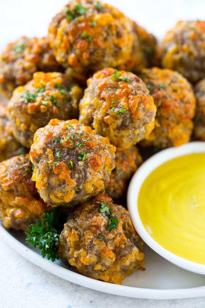 Sausage Cheese Balls Recipe | Sausage Balls Recipe | Bisquick Sausage Balls #sausage #sausageballs #balls #appetizer #cheeseballs #sraye A pile of sausage cheese balls with a side of honey mustard.