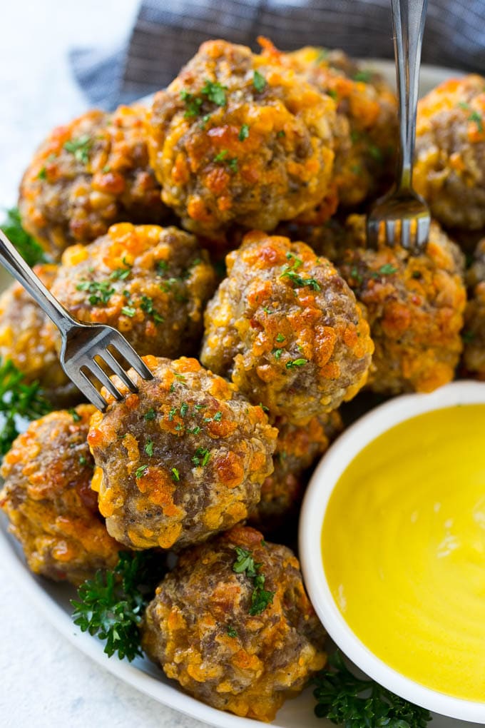 Sausage Cheese Balls Recipe | Sausage Balls Recipe | Bisquick Sausage Balls #sausage #sausageballs #balls #appetizer #cheeseballs #sraye A plate of meatballs with cocktail forks.