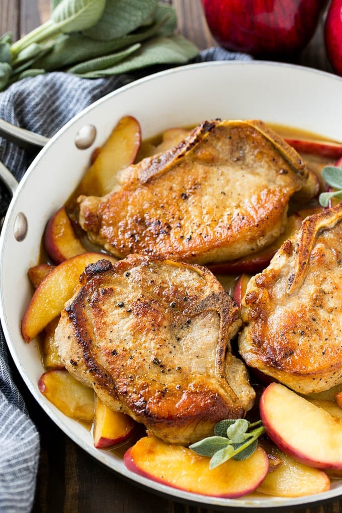 Apple Pork Chops Recipe | Pork Chops with Apples | Cider Pork Chops | Bone In Pork Chops Recipe #pork #porkchops #fall #apple #dinner #sraye A pan of apple pork chops garnished with fresh sage.