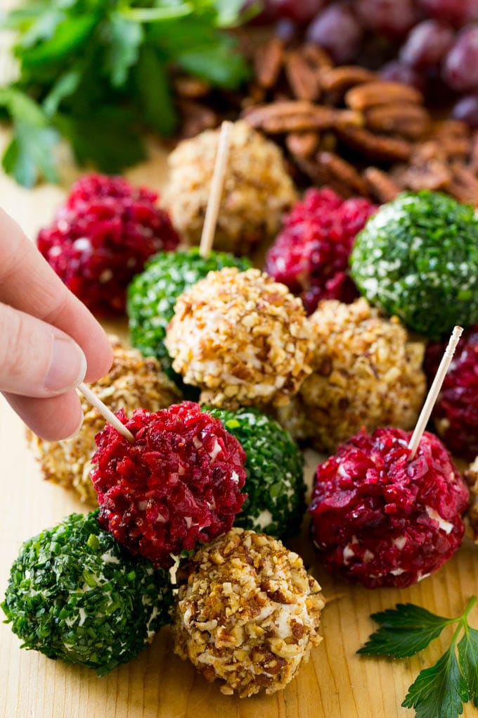 Cheese Ball Bites Recipe | Holiday Cheese Ball Recipe | Pecan Cheese Ball | Cranberry Cheese Ball | Mini Cheese Balls #cheeseball #cheese #appetizer #sraye A hand reaching for an appetizer crusted in dried craberries.