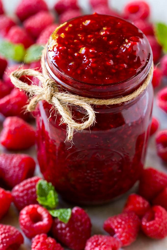Raspberry Sauce Recipe | Homemade Raspberry Sauce | Raspberry Recipe #raspberries #dessert #sraye A jar of homemade raspberry sauce surrounded by fresh raspberries.