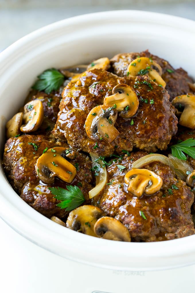 Slow Cooker Salisbury Steak Recipe | Homemade Salisbury Steak | Salisbury Steak from Scratch #steak #beef #salisbury #salisburysteak #slowcooker #crockpot #dinner #sraye A crock pot with hamburger patties, cooked mushrooms and gravy.