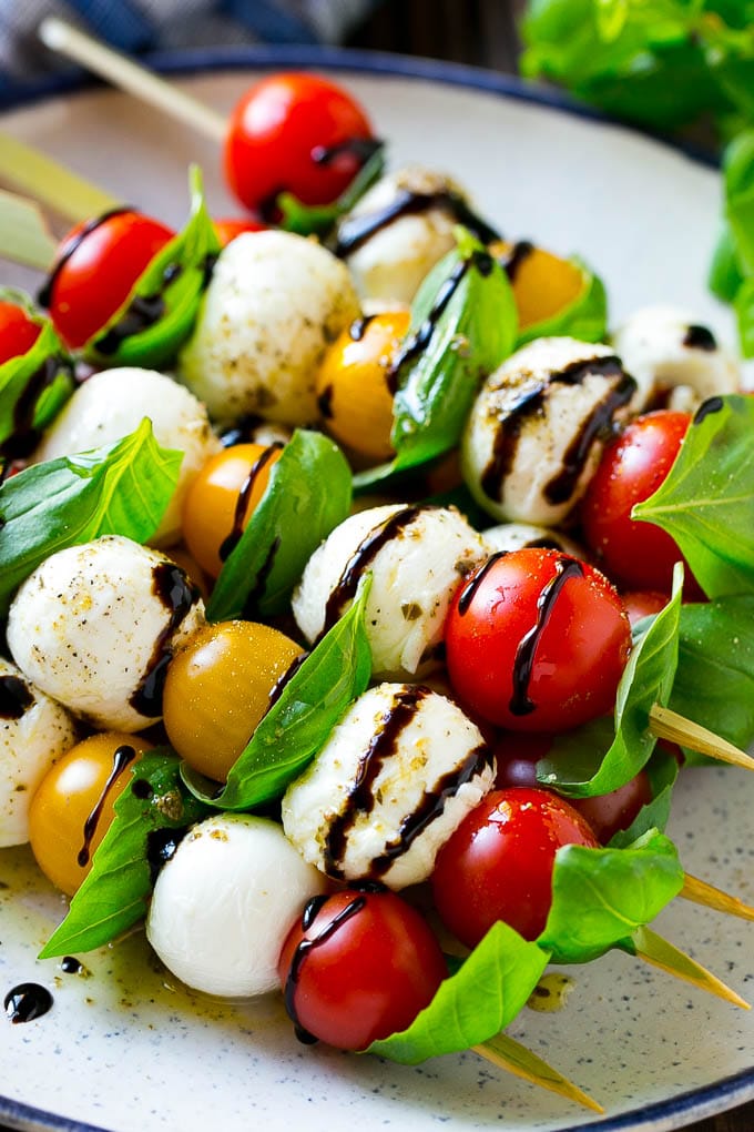 Caprese Skewers | Caprese Kabobs | Caprese Appetizer #tomato #mozzarella #basil #caprese #appetizer #sraye A plate of caprese skewers with mozzarella, tomatoes and basil.