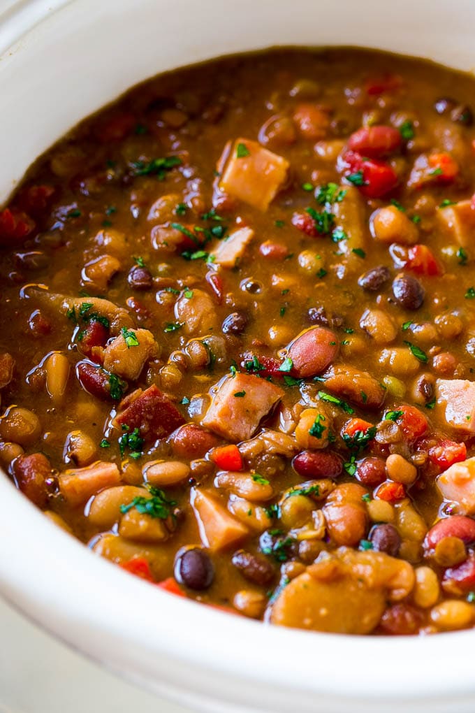 Slow Cooker Ham Bone Soup | Ham and Bean Soup | Ham Bone and Bean Soup | Ham Soup | Leftover Ham Recipe #ham #hamsoup #leftoverham #soup #slowcooker #crockpot #sraye A slow cooker full of soup with parsley on top.