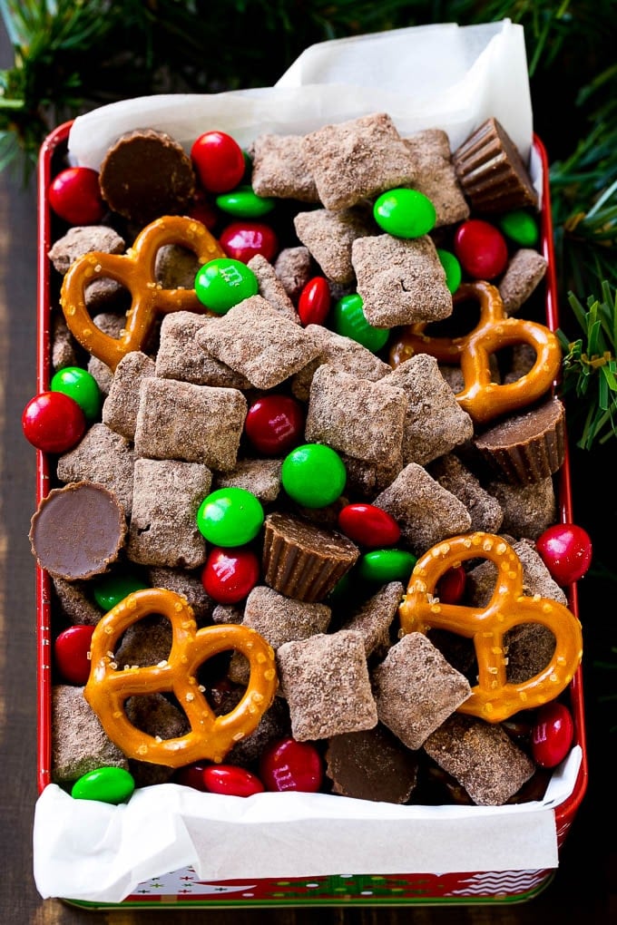 Reindeer Chow | Christmas Chex Mix | Christmas Muddy Buddies | Holiday Chex Mix #chex #chexmix #christmas #holiday #muddybuddies #reindeerchow #snack #sraye A tin of reindeer chow with chocolate coated chex, M&M's and pretzels.