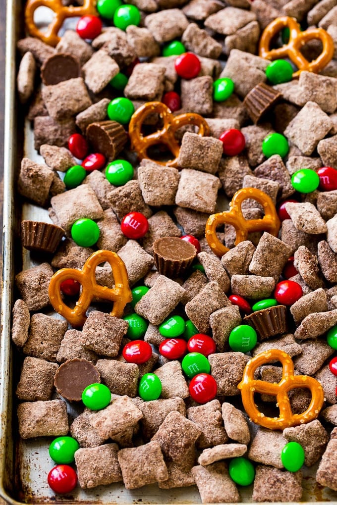 Reindeer Chow | Christmas Chex Mix | Christmas Muddy Buddies | Holiday Chex Mix #chex #chexmix #christmas #holiday #muddybuddies #reindeerchow #snack #sraye A sheet pan of Christmas muddy buddies mixed with candy and peanut butter cups.