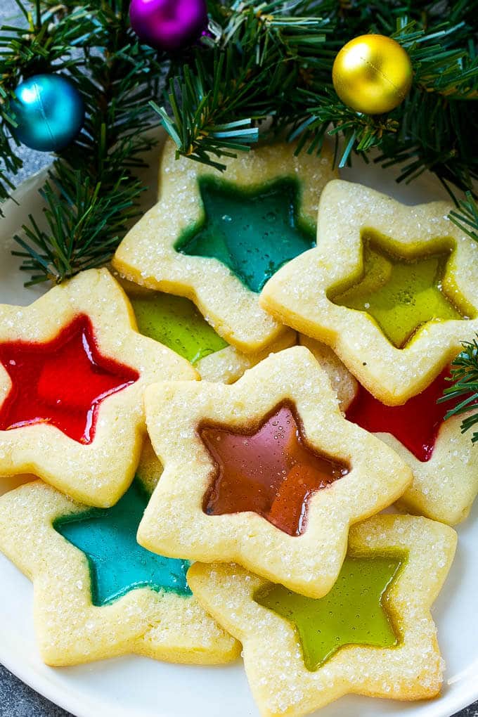 Stained Glass Cookies | Stained Glass Window Cookies | Christmas Cookies | Sugar Cookies | Holiday Cookies #cookies #stainedglasscookies #sugarcookies #christmascookies #christmas #holiday #dessert #sraye A plate of star shaped stained glass cookies with colorful centers.