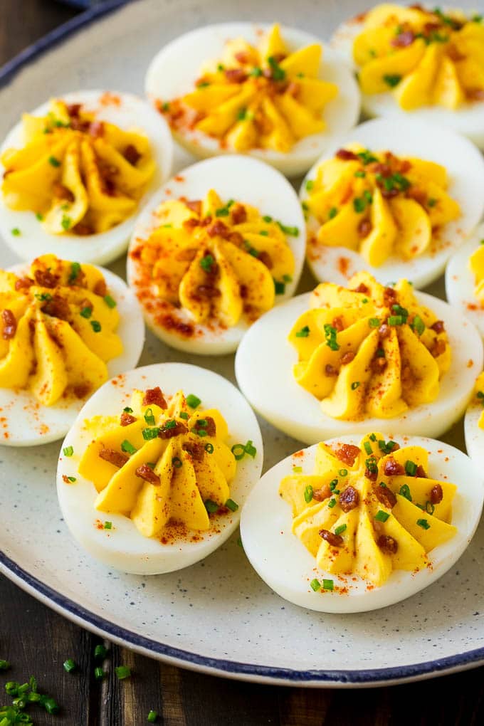 Bacon Deviled Eggs | Deviled Eggs Recipe #eggs #keto #lowcarb #bacon #appetizer #sraye A plate of bacon deviled eggs garnished with sliced chives and smoked paprika.