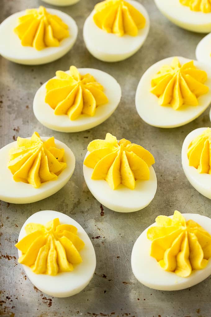 Bacon Deviled Eggs | Deviled Eggs Recipe #eggs #keto #lowcarb #bacon #appetizer #sraye Deviled eggs with a decoratively piped filling on a sheet pan.