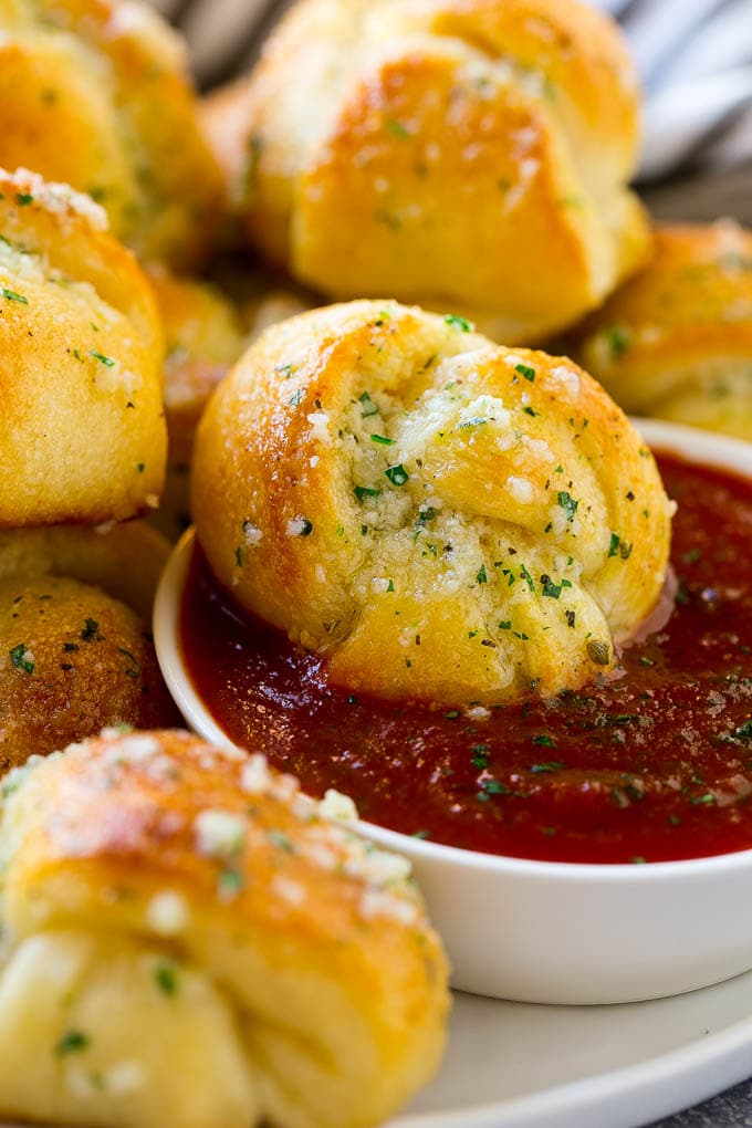 Garlic Knots Recipe | Garlic Rolls | Garlic Butter Rolls | Garlic Bread Recipe #garlic #garlicbread #garlicknots #breadsticks #sraye A garlic roll being dipped into marinara sauce for a delicious finishing touch.