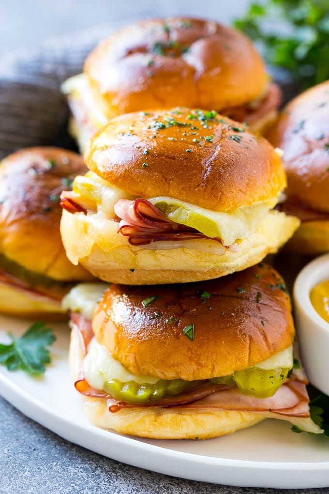 Cuban Sliders Recipe | Cuban Sandwich Recipe | Slider Sandwiches | Ham and Cheese Sliders #sliders #sandwiches #ham #cheese #appetizer #sraye A pile of cuban sliders filled with ham, cheese and pickles.