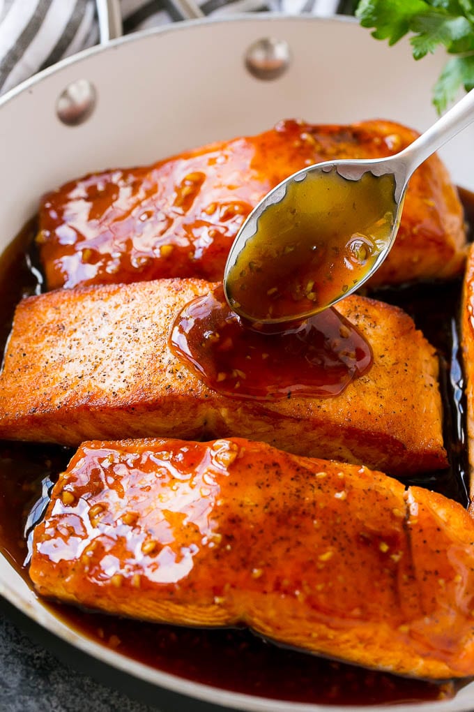 Honey Garlic Salmon Recipe | Asian Salmon Recipe | Healthy Salmon Recipe #salmon #fish #seafood #healthy #dinner #sraye A spoon pouring sauce on top of salmon fillets.