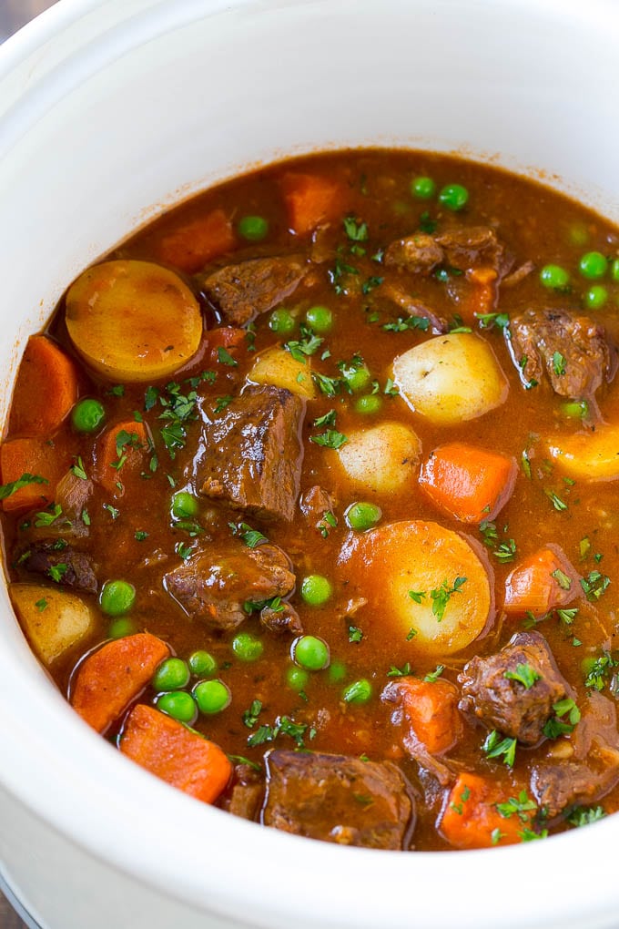 Slow Cooker Beef Stew Recipe | Beef and Potato Stew | Crock Pot Beef Stew | Easy Beef Stew #beef #beefstew #soup #slowcooker #crockpot #dinner #sraye A slow cooker full of beef stew that contains meat, potatoes, carrots and peas, all in a savory broth.