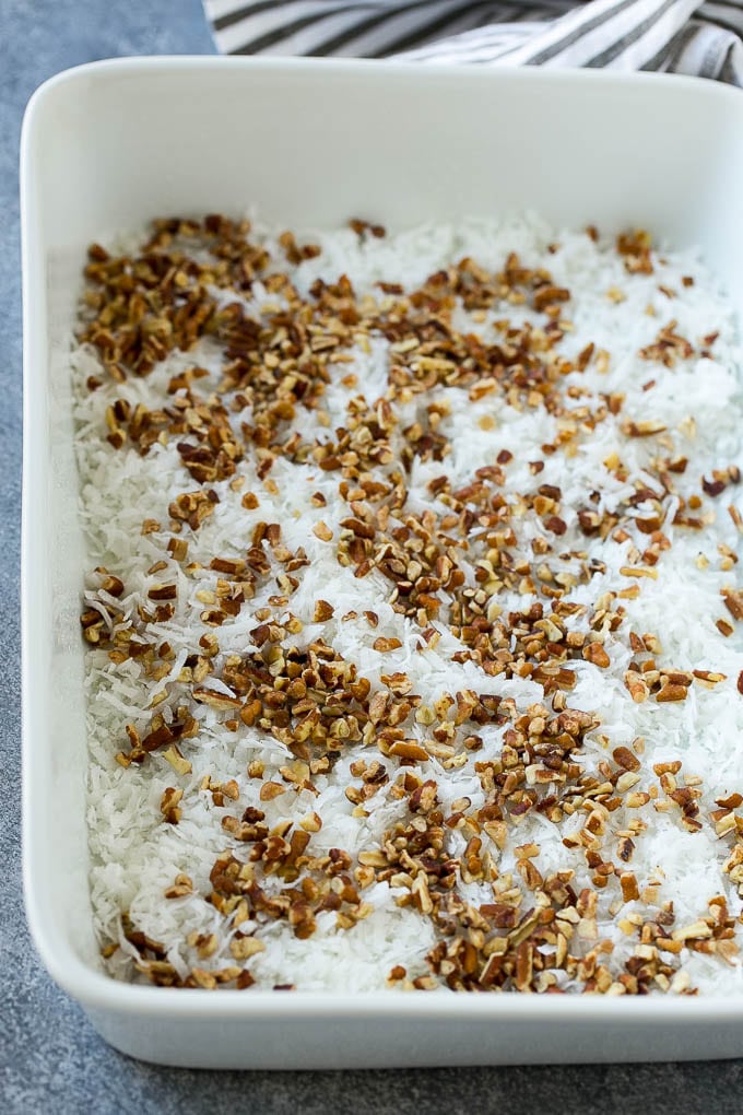 Earthquake Cake Recipe | Chocolate Cake Recipe | Chocolate Coconut Cake | Coconut Pecan Cake #cake #chocolate #coconut #pecans #dessert #chocolatecake #sraye Coconut and pecans layered into a cake pan.
