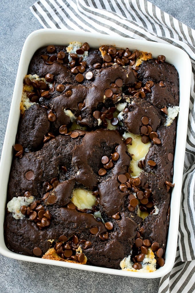 Earthquake Cake Recipe | Chocolate Cake Recipe | Chocolate Coconut Cake | Coconut Pecan Cake #cake #chocolate #coconut #pecans #dessert #chocolatecake #sraye A pan of earthquake cake topped with dollops of cream cheese and chocolate chips.