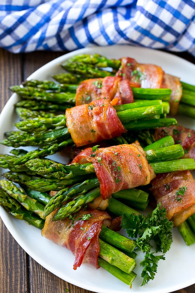 Bacon Wrapped Asparagus Recipe | Roasted Asparagus | Asparagus Side Dish #asparagus #bacon #sidedish #dinner #sraye A plate of bacon wrapped asparagus bundles garnished with parsley.