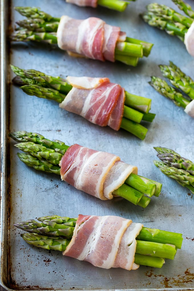 Bacon Wrapped Asparagus Recipe | Roasted Asparagus | Asparagus Side Dish #asparagus #bacon #sidedish #dinner #sraye Raw asparagus bundles on a sheet pan.