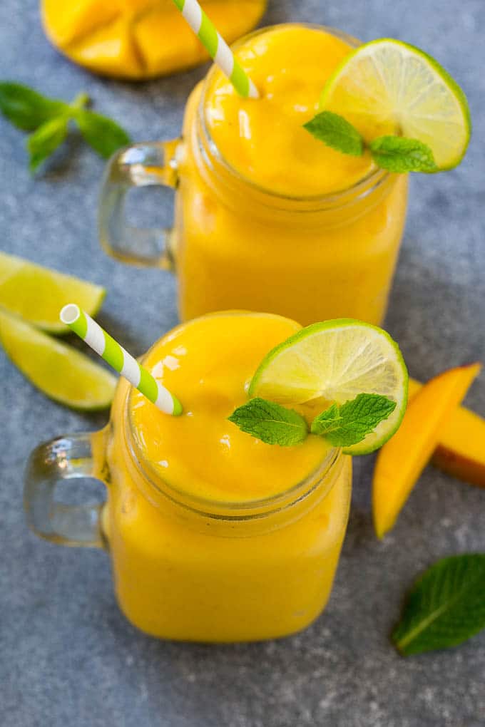 Mango Smoothie Recipe | Mango Recipe | Healthy Smoothie #mango #smoothie #drink #sraye Two jars full of mango smoothie, garnished with lime slices and fresh mint.