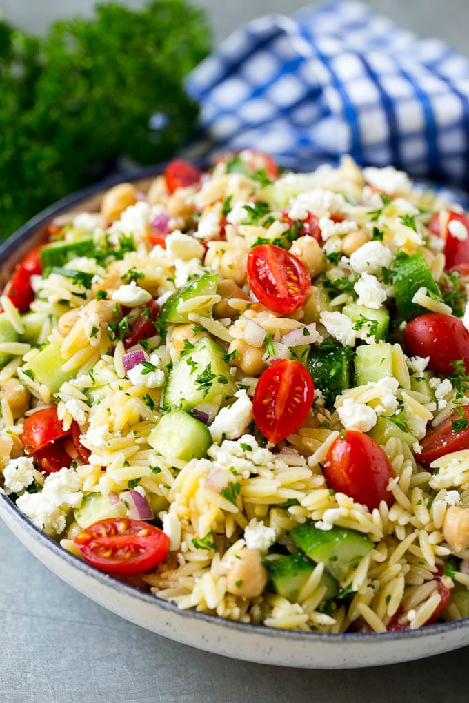 Orzo Salad Recipe | Orzo Pasta Salad | Greek Orzo Salad | Mediterranean Orzo Salad #pastasalad #orzo #greekfood #salad #sraye Orzo salad in a serving bowl with tomatoes, cucumbers and chickpeas.