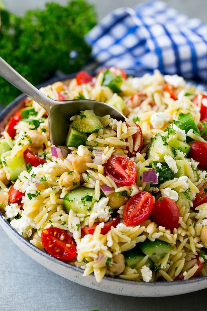 Orzo Salad Recipe | Orzo Pasta Salad | Greek Orzo Salad | Mediterranean Orzo Salad #pastasalad #orzo #greekfood #salad #sraye Orzo pasta salad with a serving spoon in the bowl.